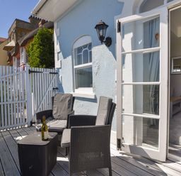 A small outdoor patio with two chairs a table a bottle of wine and two wine glasses at 1 Argyle House in Lyme Regis