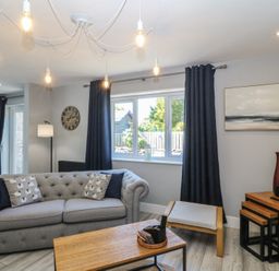 A living room with a sofa, table, and window at Ty Glan Morfa in Morfa Bychan