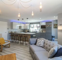 A living room with a kitchen island and bar stools at Ty Glan Morfa in Morfa Bychan