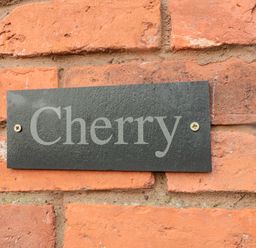 A black plaque with the word Cherry mounted on a red brick wall at Cherry Studio in Crookham near Cornhill On Tweed