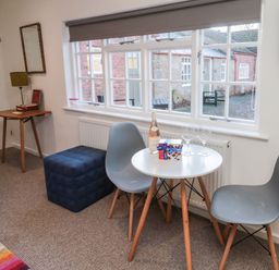 A small table with two grey chairs near a window with a bottle of wine and two glasses at Silverbirch in Crookham near Cornhill-On-Tweed