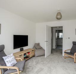 A living room with two gray armchairs a bean bag a wooden TV stand and a wall-mounted TV at 9 Lon Y Dryw in Trearddur Bay