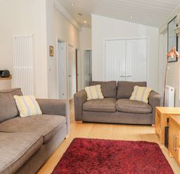 A living room with two grey sofas yellow striped cushions a red rug and wooden furniture at Garuda Calgarth 19 White Cross Bay near Windermere