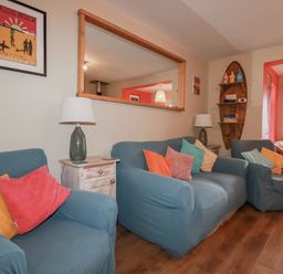 A living room with sofas and a lamp at Kippy Cottage Porthtowan