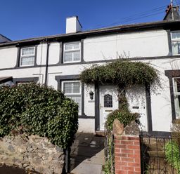 A white house with black trim and a small garden with green bushes at Glynside in Conwy
