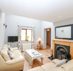 A living room with two beige sofas a coffee table a flat screen TV and a fireplace at 14 Sneem Leisure Village in Sneem County Kerry