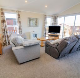 A living room with sofas coffee table television and sliding glass doors at Gressingham 22 in South Lakeland Leisure Village