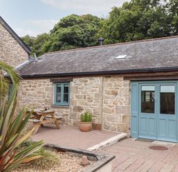 An outdoor area with a stone building with blue doors and window at Pendeen in Mawnan Smith Near Falmouth