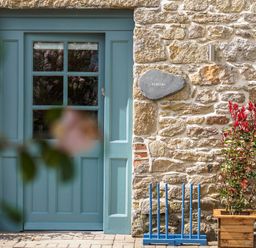 A blue door set in a stone wall with a plant in a wooden pot and a blue croquet set at Kerensa in Mawnan Smith Near Falmouth