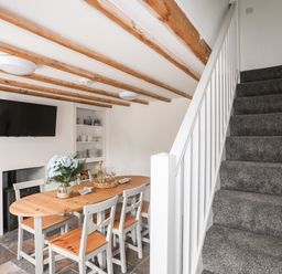 A dining area with a wooden table and chairs next to a staircase with carpet at Isfryn Llanengan near Abersoch