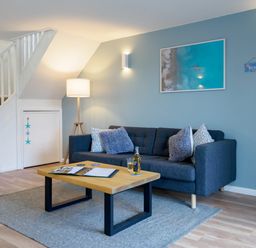 A living room with a dark grey sofa and coffee table under a staircase at Coverack in Mawnan Smith Near Falmouth