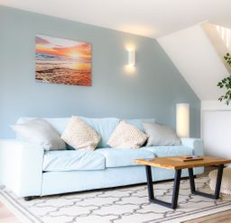 A blue sofa with cushions a wooden coffee table and a potted plant in a living room at Sennen in Mawnan Smith Near Falmouth