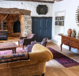 A living room with a wood stove fireplace leather chairs a wooden coffee table and a wooden sideboard at Henllys in Newport Pembrokeshire