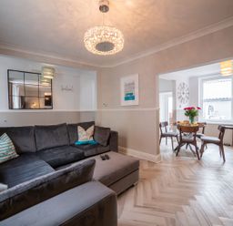 A living room with a gray sectional sofa and pillows opening to a dining area with a round table and chairs at Green Retreat in Dartmouth
