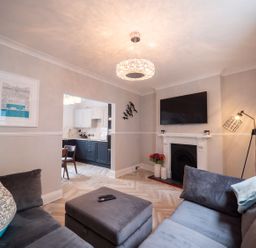A living room with grey sofas a wall-mounted TV and a view into the kitchen at Green Retreat in Dartmouth