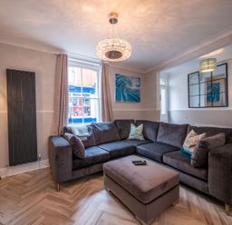 A living room with a large sectional sofa ottoman floor lamp and wall art at Green Retreat in Dartmouth