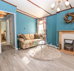 A living room with a floral sofa glass coffee table and fireplace at Lodge Two Country View Park in Graveney