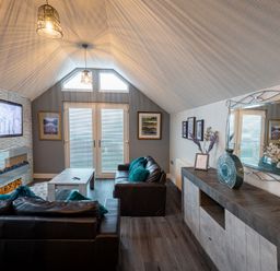 A living room with two leather sofas a coffee table a wall-mounted TV and a sideboard with a mirror at Lakeland Lodge in Carnforth