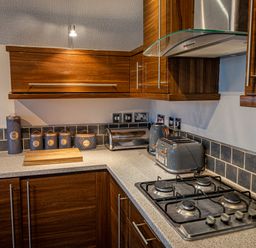 A kitchen corner with gas stove toaster kettle and storage canisters at Lakeland Lodge in Carnforth
