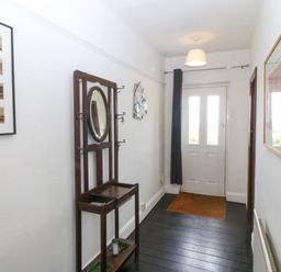 A hallway with a coat rack and photographs at Faraway in Rhosneigr