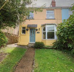 The front exterior of a two-story house with a blue door, bay window, and garden path at Greengate in Tenby