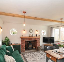 A living room with a green sofa wooden table and a brick fireplace at Rosemary Cottage in Briggswath near Sleights