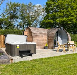 A wooden pod with outdoor hot tub and patio furniture in a garden at Y Dderwen Bontuchel near Ruthin