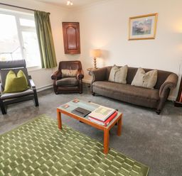 A living room with two armchairs a sofa and a small table with books at 8 Oaks Field Ambleside