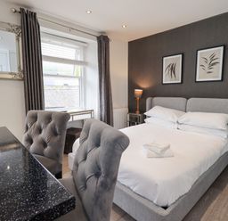 A bedroom with a bed and a table at Bowness Central in Bowness-On-Windermere