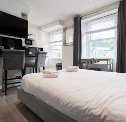 A bedroom with a bed and kitchen area at Bowness Central in Bowness-On-Windermere