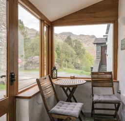 A conservatory with a table and chairs at Woodloft Cottage Elterwater near Chapel Stile