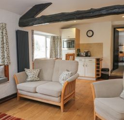 A living room with seating and kitchen appliances at Woodloft Cottage Elterwater near Chapel Stile