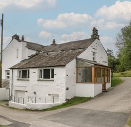 Exterior view of a house with a pathway and trees at Woodloft Cottage Elterwater near Chapel Stile