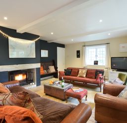 A living room with leather sofas a wooden bench a fireplace and a television at Durdans Walberswick