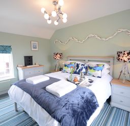 A bedroom with a double bed pillows and bedside tables with lamps at Bunny Cottage Aldeburgh
