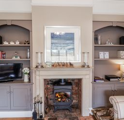 A living room with a television and fireplace at Holly Lodge in Aldeburgh
