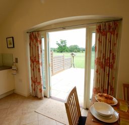 A dining area with a set table next to glass doors leading to a garden at Remus Larling near East Harling