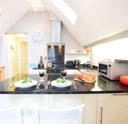 A kitchen with black countertops two place settings and various appliances at Pied a Mer Aldeburgh