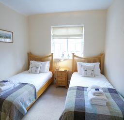 A bedroom with two single beds and a bedside table between them at The Hideaway in Aldeburgh