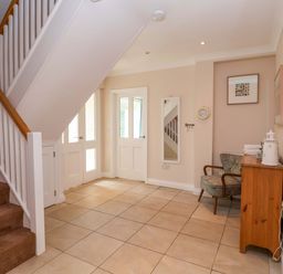 A hallway with a staircase and a chair at Seadrift Dunwich Near Westleton