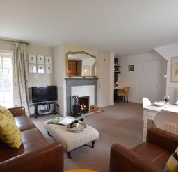A living room with brown sofas a fireplace a dining table and chairs a television and a desk at Rookyards Spexhall Near Halesworth