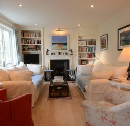 A living room with sofas a fireplace bookshelves and lamps at 2 The Bays Thorpeness