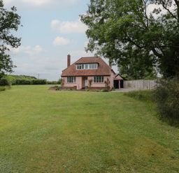 A detached house with a tiled roof and grass lawn surrounded by trees at Ash Tree Cottage Aldringham