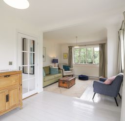 A living room with a green sofa a white armchair a blue armchair a wooden chest as a coffee table and wooden cabinet at Ash Tree Cottage Aldringham