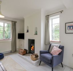 A living room with a blue armchair and a fireplace with fire at Ash Tree Cottage Aldringham