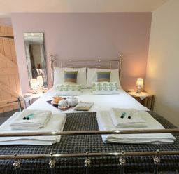 A bedroom with a metal bed frame a bed with pillows towels and tea set at Yew Tree Farm Barn Worlingworth near Framlingham