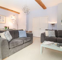 A living room with two grey sofas a coffee table and a dining area at Saffron Blythview in Blythburgh near Southwold