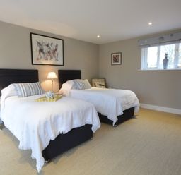 A bedroom with two single beds lamps a window and a standing mirror at Bird Cottage Burgh Near Grundisburgh