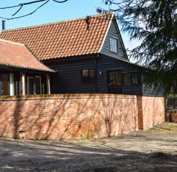 A building with a tiled roof black wooden walls and a brick wall in front at Bird Cottage Burgh Near Grundisburgh