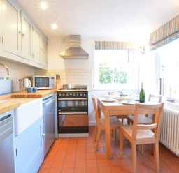 A kitchen with wooden countertops dining table with chairs and kitchen appliances at 1 South Cottages in Thorpeness